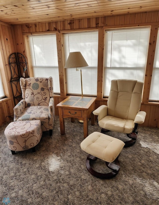 living area featuring plenty of natural light, carpet, wooden ceiling, and wooden walls