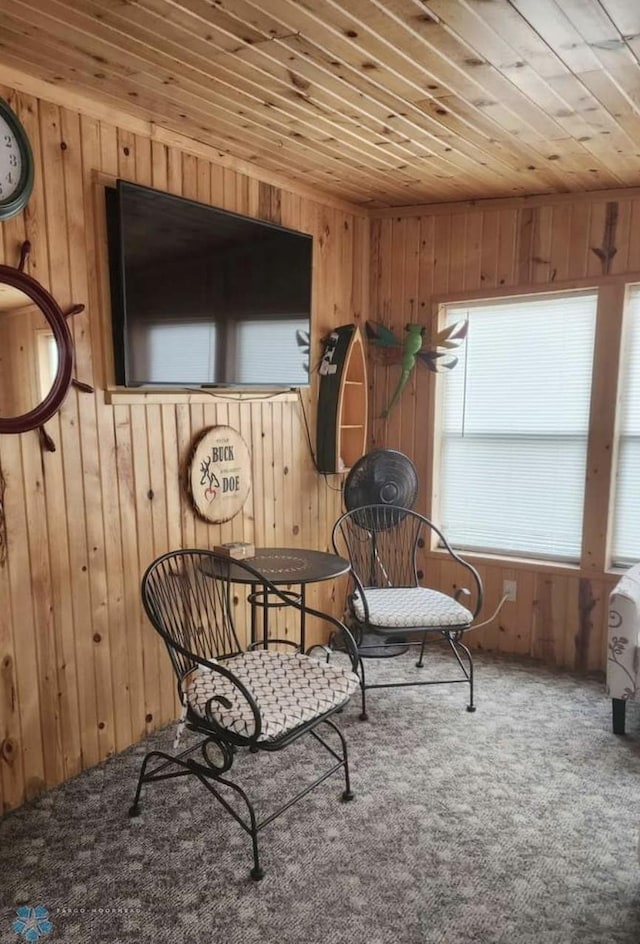 sitting room with wooden ceiling, carpet flooring, and wood walls