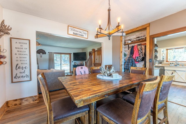 dining space featuring a chandelier, stairway, and wood finished floors