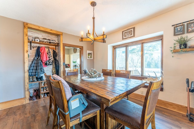 dining space with an inviting chandelier, wood finished floors, baseboards, and a textured ceiling