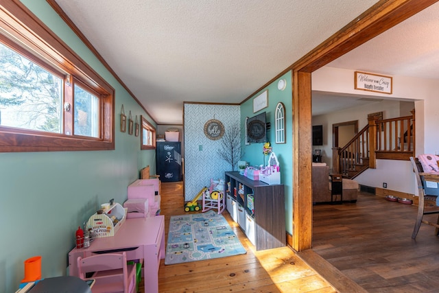 game room featuring visible vents, ornamental molding, a textured ceiling, wood finished floors, and baseboards