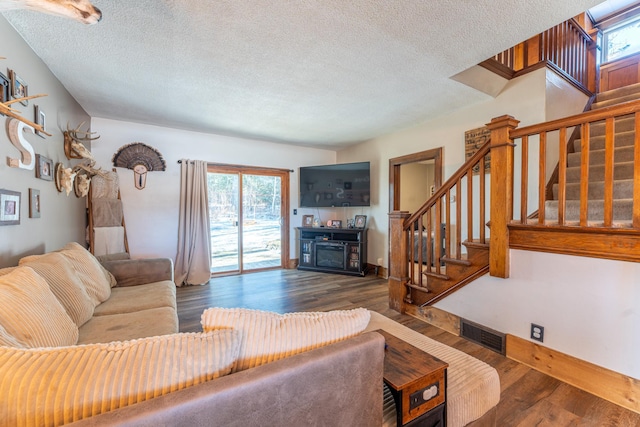 living room with stairway, a textured ceiling, visible vents, and wood finished floors