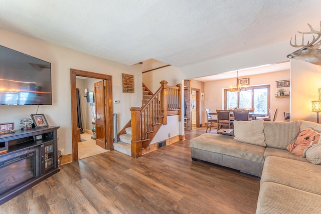 living area with visible vents, a textured ceiling, wood finished floors, stairway, and an inviting chandelier