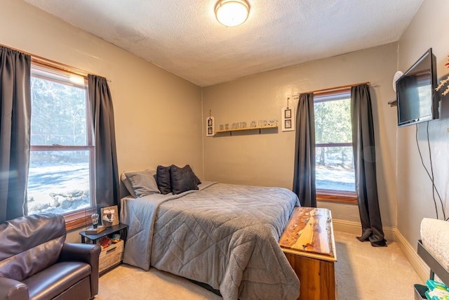 bedroom featuring baseboards, light carpet, and a textured ceiling