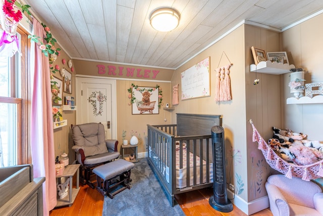 bedroom featuring wood finished floors, ornamental molding, and wooden ceiling