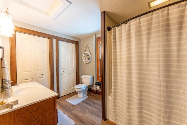 full bathroom featuring curtained shower, toilet, vanity, and wood finished floors