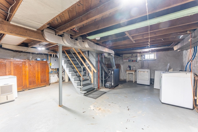 below grade area featuring electric panel, stairway, washing machine and dryer, and heating unit