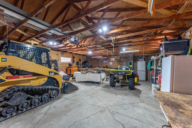 garage with a workshop area, a garage door opener, and freestanding refrigerator