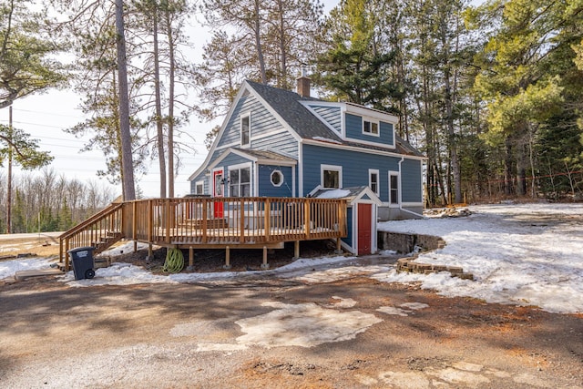 view of front of home featuring a wooden deck, a chimney, and a shingled roof