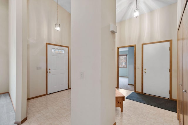 entrance foyer with tile patterned floors, baseboards, and a high ceiling