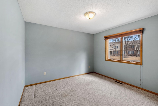 carpeted empty room with baseboards, visible vents, and a textured ceiling