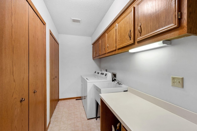 washroom featuring visible vents, baseboards, washing machine and dryer, cabinet space, and a textured ceiling