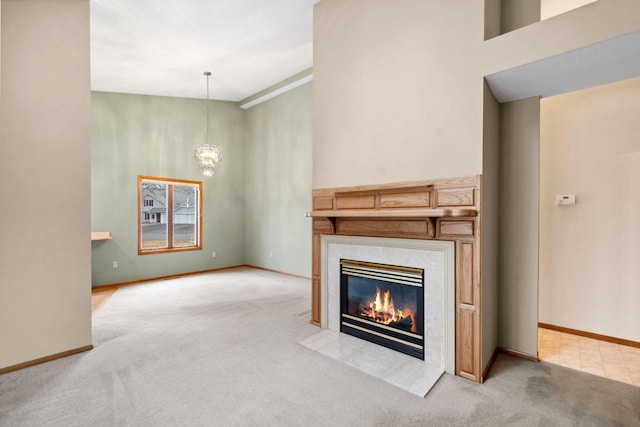 unfurnished living room with an inviting chandelier, baseboards, carpet, and a premium fireplace