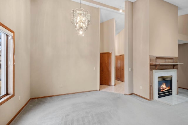 unfurnished living room featuring a glass covered fireplace, baseboards, carpet, and a towering ceiling