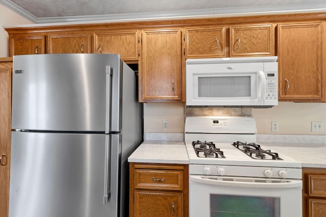 kitchen featuring white appliances, ornamental molding, brown cabinetry, and light countertops