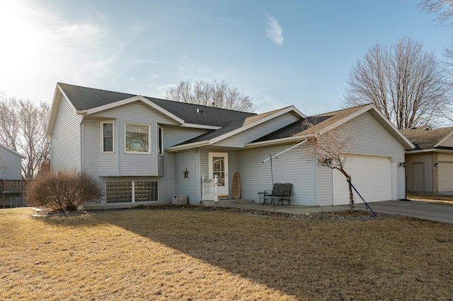 tri-level home featuring a front lawn, a garage, driveway, and a shingled roof