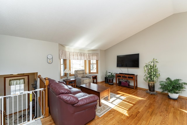 living area featuring baseboards, lofted ceiling, and wood finished floors