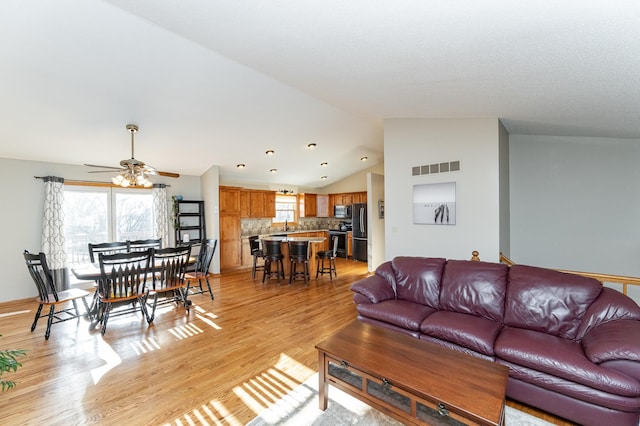 living room with lofted ceiling, plenty of natural light, visible vents, and light wood-type flooring