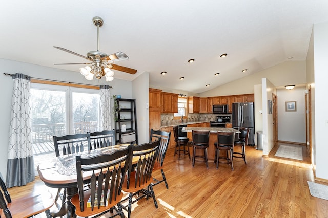 dining room with lofted ceiling, a ceiling fan, baseboards, and light wood finished floors