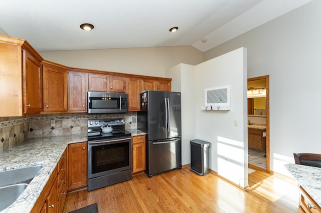 kitchen featuring lofted ceiling, brown cabinets, appliances with stainless steel finishes, and light wood-type flooring