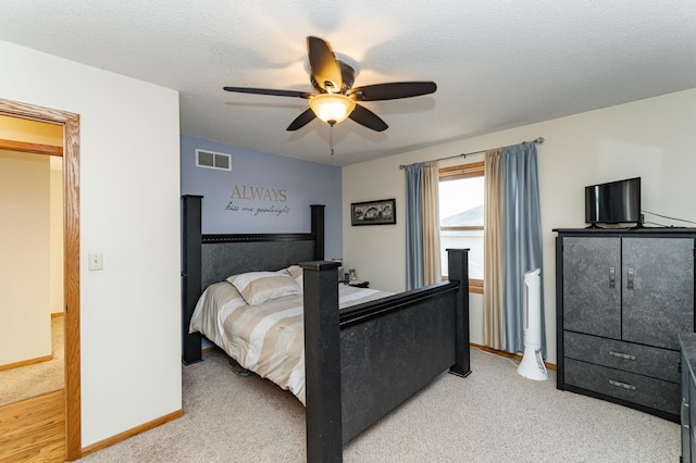 bedroom featuring visible vents, baseboards, ceiling fan, light carpet, and a textured ceiling