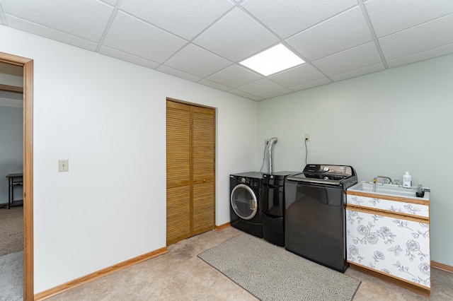 clothes washing area with washing machine and clothes dryer, baseboards, and a sink