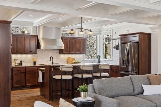 38 Mississippi River Blvd N, Saint Paul, MN 55104 - kitchen featuring stainless steel fridge with ice dispenser, wall chimney exhaust hood, open floor plan, light wood-style flooring, and a breakfast bar