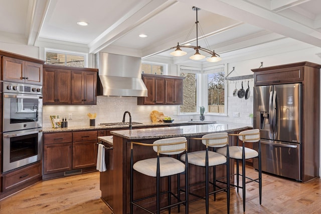 38 Mississippi River Blvd N, Saint Paul, MN 55104 - kitchen featuring appliances with stainless steel finishes, wall chimney range hood, beamed ceiling, stone countertops, and light wood-type flooring