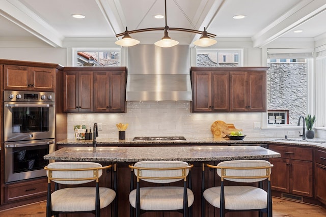38 Mississippi River Blvd N, Saint Paul, MN 55104 - kitchen with a sink, stainless steel appliances, wall chimney range hood, a breakfast bar, and wood finished floors