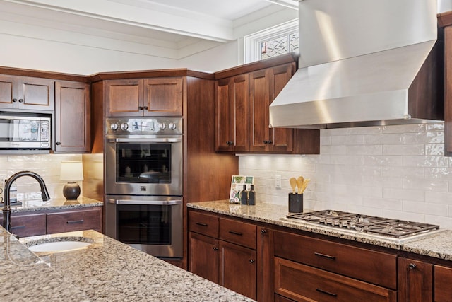 38 Mississippi River Blvd N, Saint Paul, MN 55104 - kitchen with appliances with stainless steel finishes, wall chimney range hood, a sink, backsplash, and light stone counters