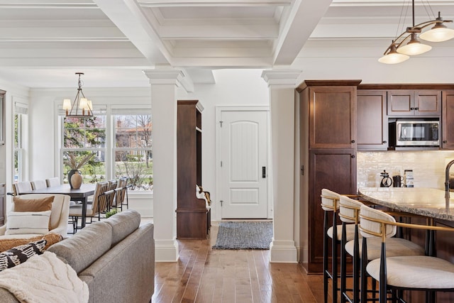 38 Mississippi River Blvd N, Saint Paul, MN 55104 - kitchen with stainless steel microwave, decorative columns, beamed ceiling, hardwood / wood-style flooring, and a kitchen breakfast bar