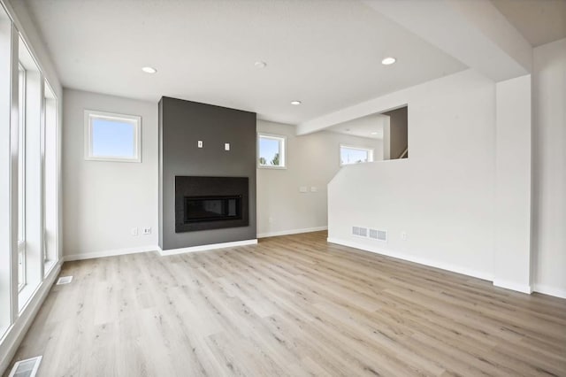 unfurnished living room featuring visible vents, plenty of natural light, and wood finished floors