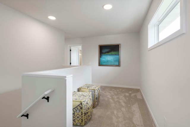 hall with an upstairs landing, recessed lighting, light carpet, and baseboards