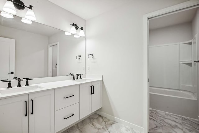 bathroom with double vanity, marble finish floor, baseboards, and a sink