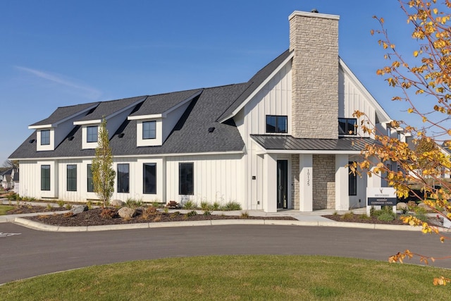 modern inspired farmhouse featuring board and batten siding, roof with shingles, and a chimney