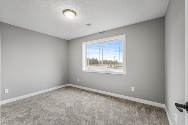 spare room featuring carpet flooring, a textured ceiling, and baseboards