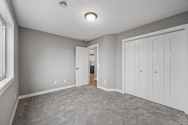 unfurnished bedroom with carpet, baseboards, a closet, and a textured ceiling