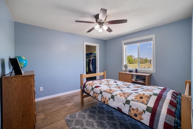 18492 120th St SE, Big Lake, MN 55309 - bedroom with wood finished floors, a textured ceiling, a ceiling fan, and a walk in closet