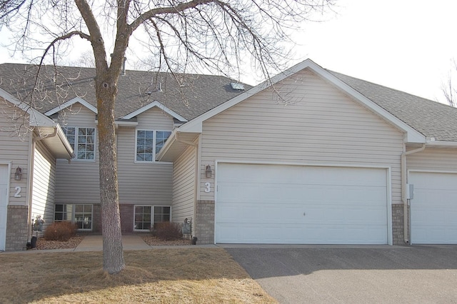 view of front of home with driveway, a garage, and roof with shingles