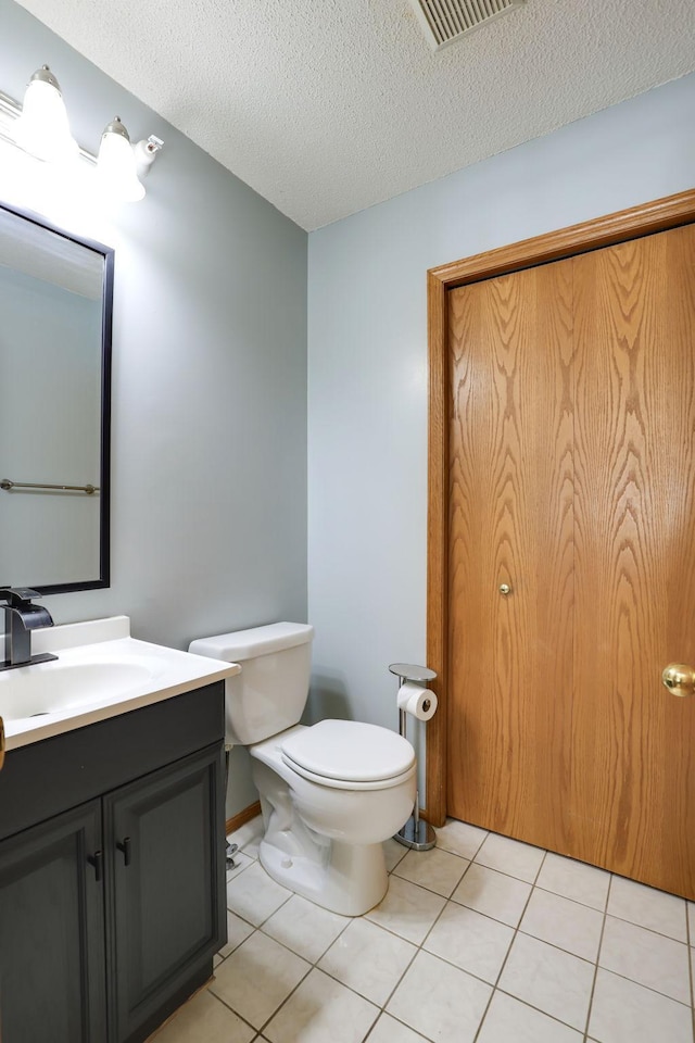 half bath with vanity, visible vents, a textured ceiling, tile patterned floors, and toilet