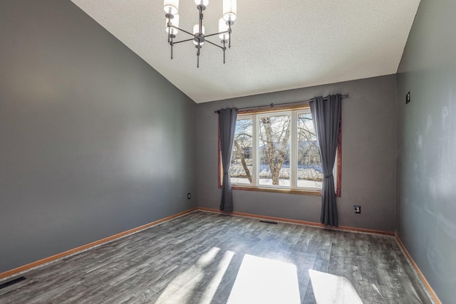 unfurnished room featuring vaulted ceiling, a notable chandelier, wood finished floors, and baseboards