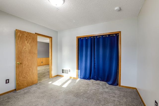 carpeted spare room with baseboards, visible vents, and a textured ceiling