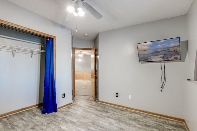 unfurnished bedroom with a ceiling fan, wood finished floors, a closet, and baseboards