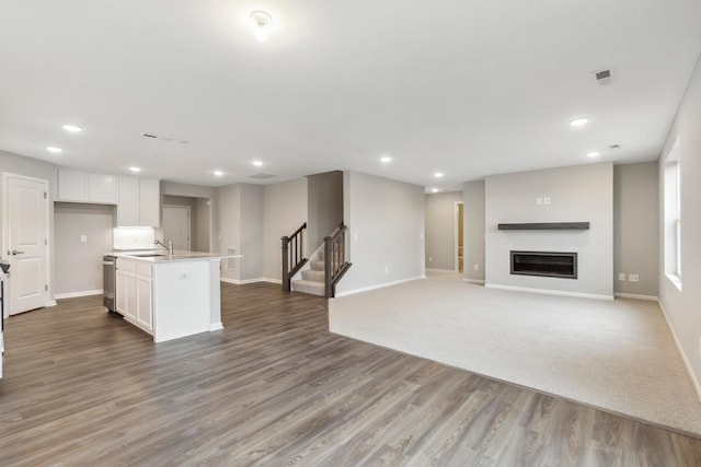 unfurnished living room featuring recessed lighting, stairs, and baseboards