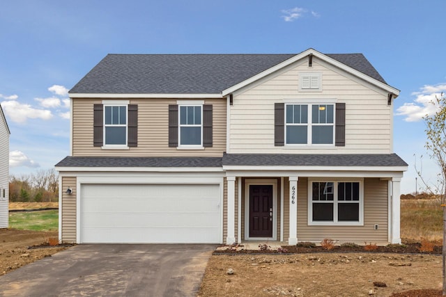 traditional-style home featuring driveway, an attached garage, and a shingled roof