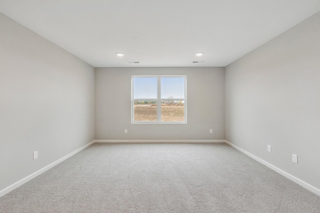 spare room featuring visible vents, light colored carpet, and baseboards