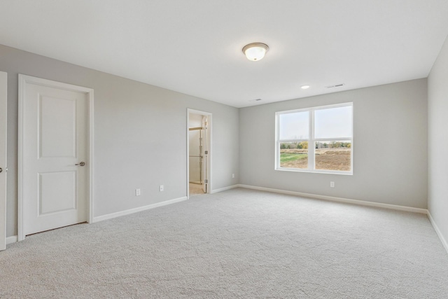 unfurnished room featuring visible vents, baseboards, and light colored carpet