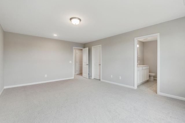 unfurnished bedroom with ensuite bath, light colored carpet, and baseboards