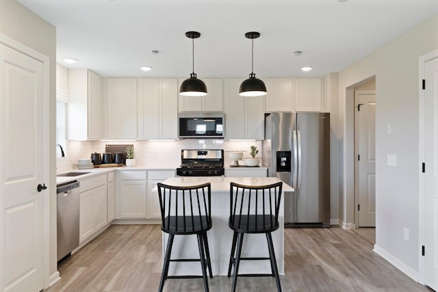 kitchen featuring light wood-style flooring, a sink, stainless steel appliances, tasteful backsplash, and a center island