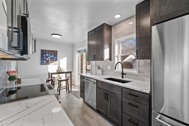 kitchen with dark brown cabinetry, decorative backsplash, appliances with stainless steel finishes, and a sink